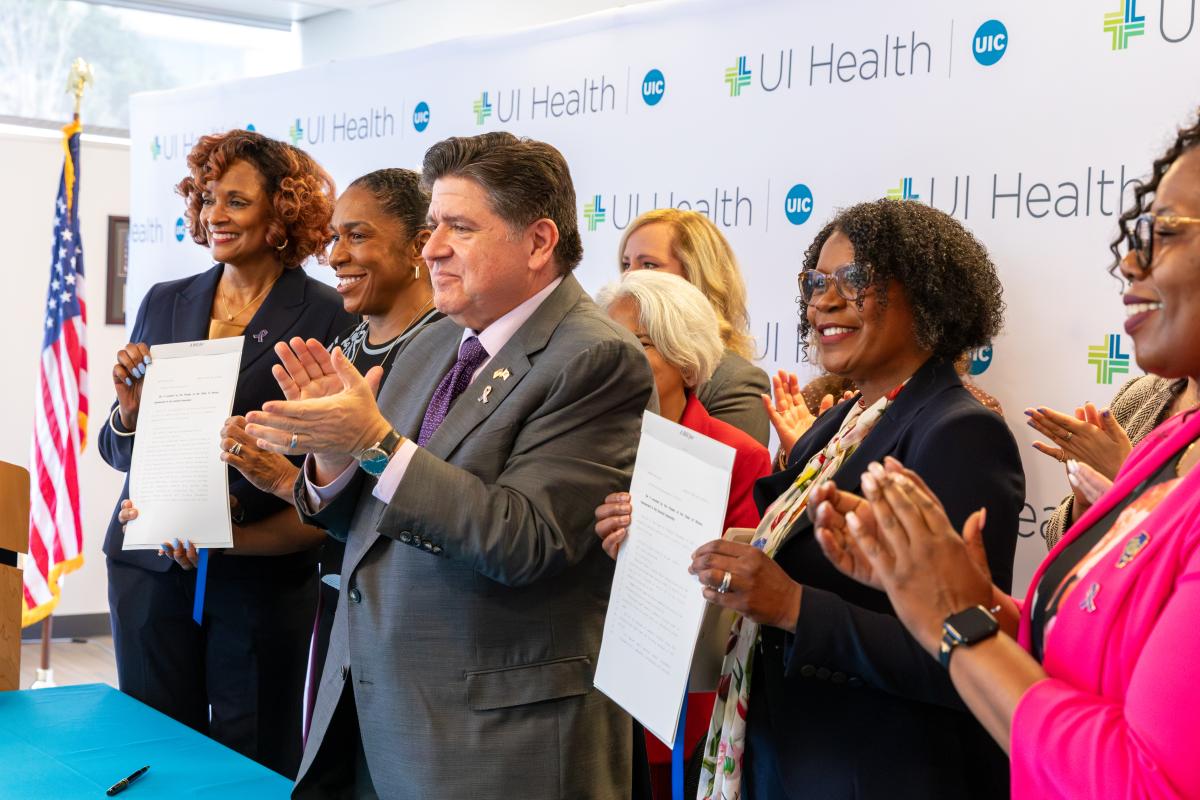 State Senator Adriane Johnson, Governor JB Pritzker and others holding signed bills